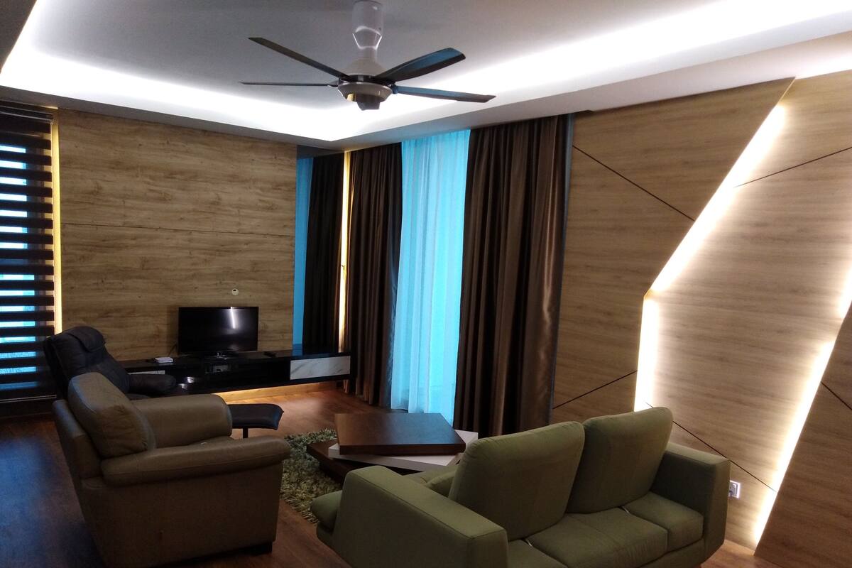 A modern living room with a flat-screen TV, two sofas, a coffee table, and a ceiling fan.