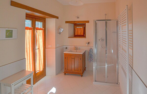 Un baño con un mueble de madera, un lavabo, un espejo y una cabina de ducha de vidrio.