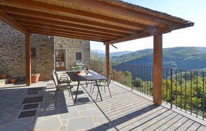 Un edificio de piedra con un patio y pérgola de madera.