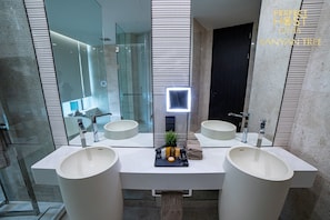Bathroom features two oval-shaped sinks with sleek faucets and a large mirror.