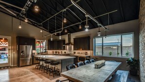 A modern kitchen with a central island, bar stools, and a large dining table.