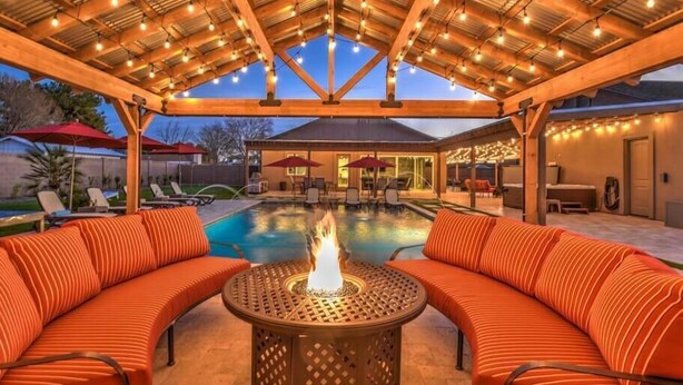 An outdoor patio area with a pool, orange-striped seating, and a fire pit.