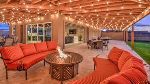 An outdoor patio with a fire pit, seating, and string lights.