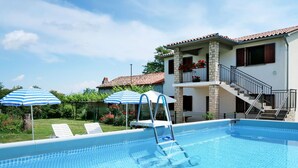 Une piscine avec un escalier, des chaises longues et des parasols à rayures.
