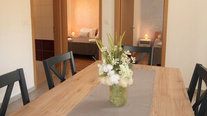Un coin repas avec une table en bois, des chaises noires et un vase rempli de fleurs.