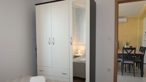 Une chambre avec une grande armoire, une table de chevet avec une lampe et un lit soigneusement fait.