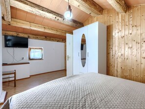 A bedroom with a bed, a wardrobe, a television, and a window.