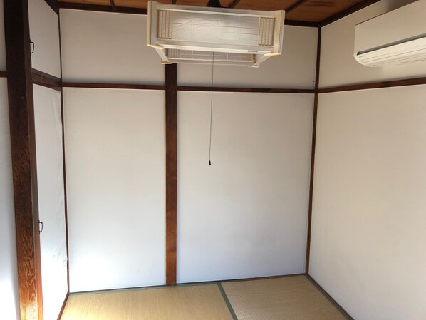 Une pièce dotée d’un sol recouvert de tatamis, d’une porte coulissante et d’un ventilateur de plafond.