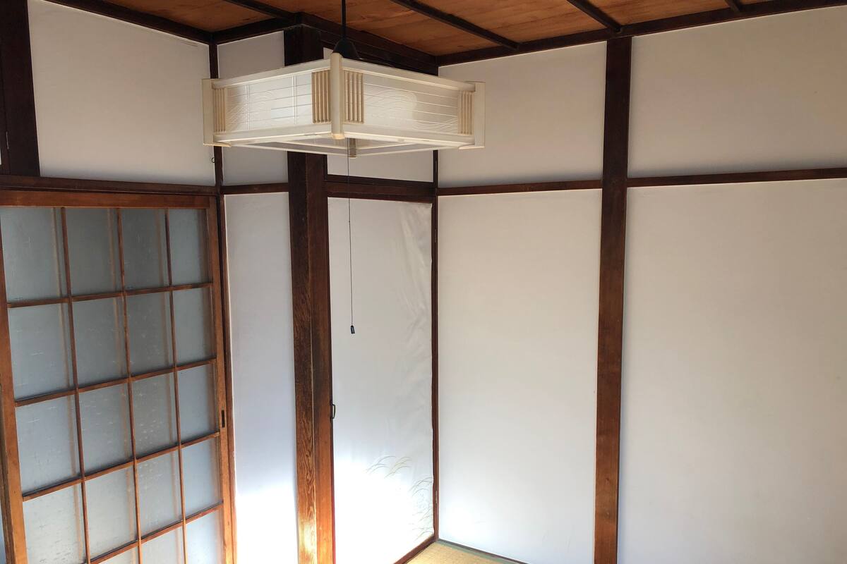 Une pièce de style japonais traditionnel, avec un sol recouvert de tatamis, des paravents shoji et un luminaire suspendu.