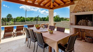 Une terrasse extérieure avec une table et des chaises, une cheminée en briques et une vue sur le paysage environnant.