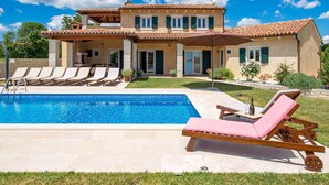 Une maison à deux étages dotée d’une piscine, d’un espace extérieur aménagé et d’un jardin bien entretenu.