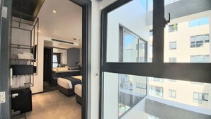 Una habitación de hotel moderna con un ventanal grande, una cama, un escritorio y un baño.