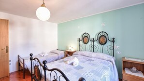 Ein Schlafzimmer mit zwei Einzelbetten, einer Holztür, einer Pendelleuchte und einem kleinen Nachttisch mit Lampe.