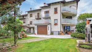 Ein mehrgeschossiges Wohngebäude mit Innenhof, Holztür zur Garage und Balkonen mit Geländern.