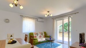 A modern living room with a sofa, a dining table with chairs, a small round table with a vase, and a television on a wooden cabinet. - Wonderful private villa for 6 people with WIFI, A/C, private pool, TV and terrace (Labin)