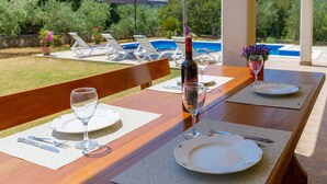 A dining table set for two with wine glasses, plates, and cutlery, overlooking a pool and garden. - Wonderful private villa for 6 people with WIFI, A/C, private pool, TV and terrace (Labin)