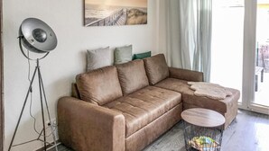 A living room with a brown leather sofa, a floor lamp, a small round table, and a painting on the wall. - 1 bedroom stunning apartment in Graal Müritz (Graal Müritz)