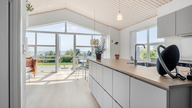 Eine moderne Küche mit großen Fenstern, einem Essbereich und Blick ins Freie.
