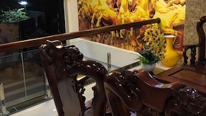 A dining area with ornate wooden chairs and a table, a mural with horses, and a modern ceiling light fixture. - New Day Hotel Quy Nhon (Quy Nhon Nam)