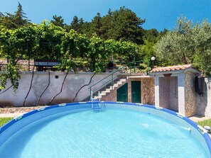 Relax by the pool surrounded by lush surroundings and a staircase leading to an upper level.