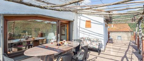Un patio luminoso con un tavolo rotondo e sedie, vista sulla campagna, e uno stile architettonico rustico.