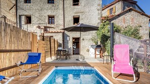 A swimming pool with wooden deck, two lounge chairs, a table, and a chair. - Beautiful apartment for 5 guests with WIFI, private pool, TV and pets allowed (Lugnano-monti Di Villa)