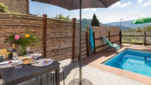 A poolside area with a table set for dining, a large umbrella providing shade, and a view of mountains in the background. - Beautiful apartment for 5 guests with WIFI, private pool, TV and pets allowed (Lugnano-monti Di Villa)