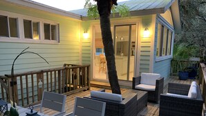 A wooden deck with outdoor furniture, a glass door leading to a kitchen, and a potted plant. - Unwind at our beautifull dog friendly beach with private access! (Vero Beach)