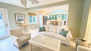 A spacious living room with a white sofa set, a coffee table, and a ceiling fan. - Unwind at our beautifull dog friendly beach with private access! (Vero Beach)