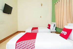 Ein Hotelzimmer mit zwei Betten, jeweils mit einer rot-weißen Decke, einem an der Wand befestigten Flachbildfernseher und beigen Vorhängen.
