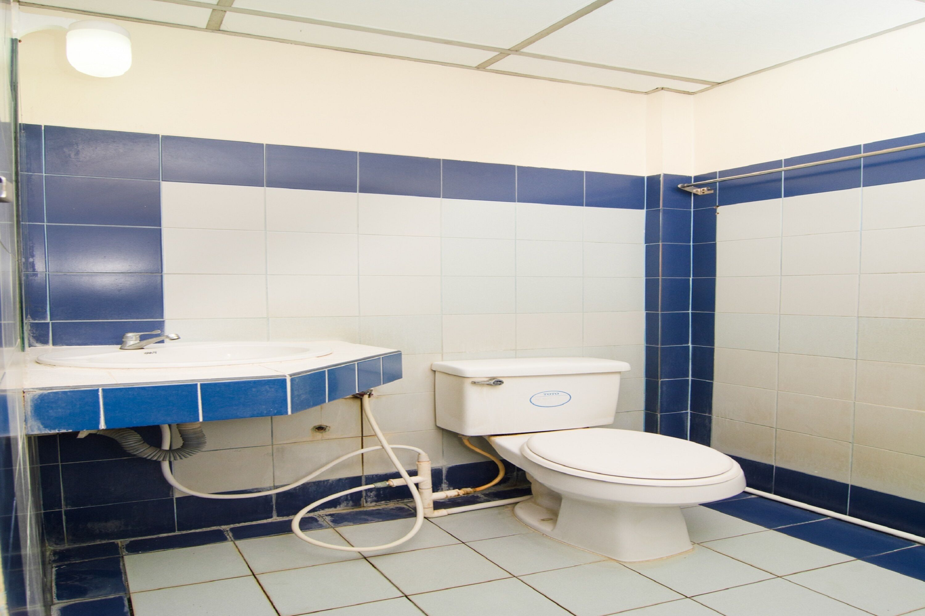 Une salle de bain avec des toilettes, un lavabo et des murs recouverts de carreaux bleus.
