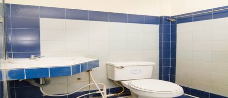 Une salle de bain avec des toilettes, un lavabo et des murs recouverts de carreaux bleus.