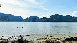 A calm lake with rocky shorelines and distant mountains under a clear sky. - OYO Bulan Anda Baba Resort (Ao Luek)