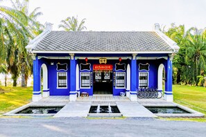 A traditional building with a tiled roof, blue walls, and a central entrance with a red sign. - OYO Bulan Anda Baba Resort (Ao Luek)