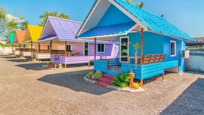 Une rangée de maisons colorées aux toits distinctifs, un sol recouvert de gravier et un ciel dégagé.