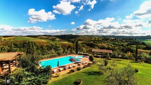 Um resort com piscina, espreguiçadeiras e vista para o campo circundante.