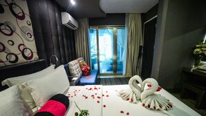 A hotel room with a neatly made bed, a sofa, and a view of the outdoors. - Maria Eloisa Royal House (Daanbantayan)