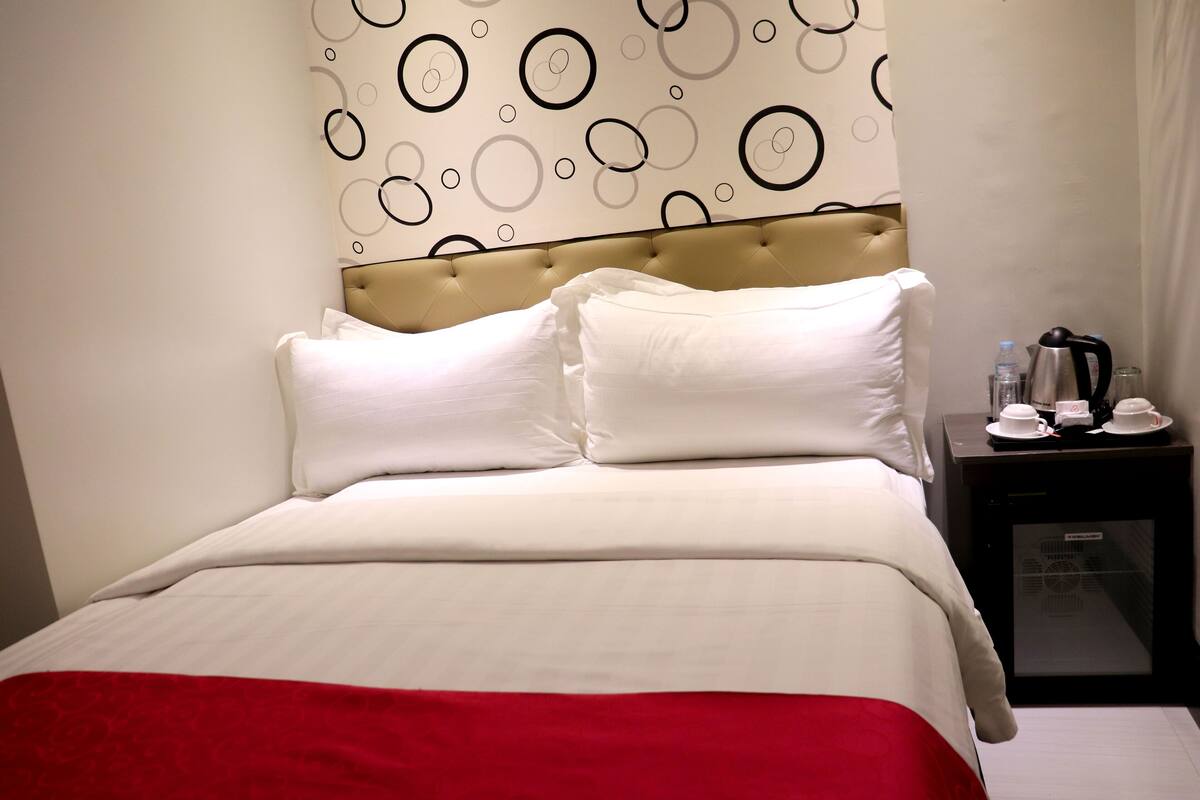Une chambre d’hôtel avec un lit, une table de chevet et un mur orné de motifs circulaires.