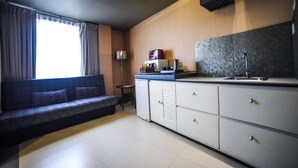 A modern kitchen with a built-in stove, a sink, and a microwave. There is a small dining table and a sofa in the living area. - Maria Eloisa Royal House (Daanbantayan)
