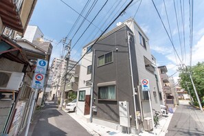 A narrow urban street with residential buildings, utility poles, and street signs indicating parking restrictions. - Mori House In Nishinippori (Tokyo)