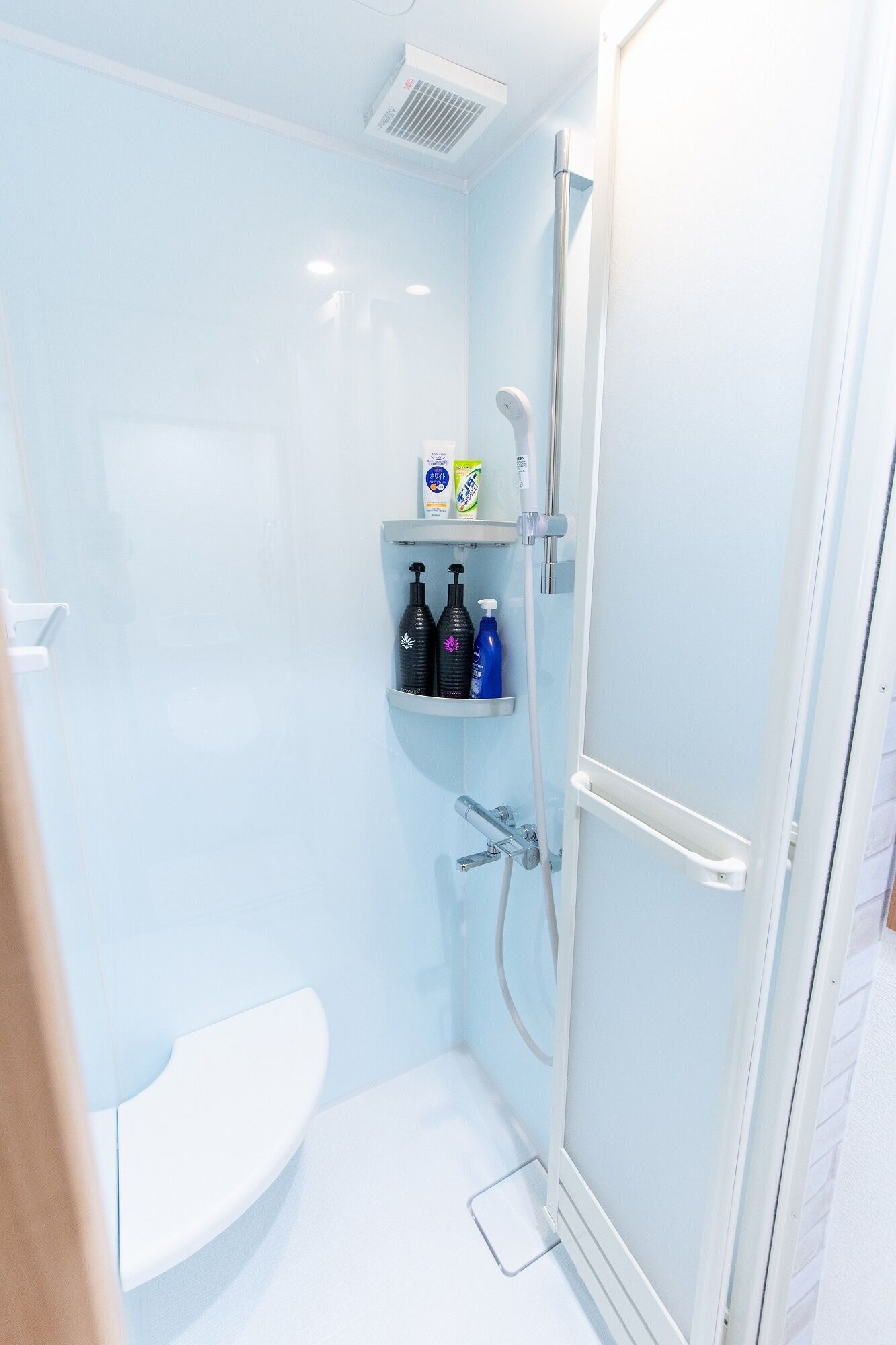 Een moderne badkamer met een douchecabine van glas, een witte wastafel en een plank met toiletartikelen.