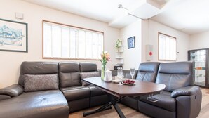A modern living room with leather sofas, a wooden coffee table, and a dining table set for two. - Mori House In Nishinippori (Tokyo)