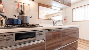 A modern kitchen with a built-in dishwasher, a stove, and a large mirror above the sink. - Mori House In Nishinippori (Tokyo)