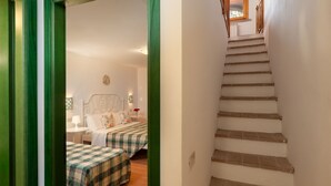 A bedroom with two beds, a nightstand, a wall clock, and a staircase leading to an upper floor. - Apartment with A/C, pool, WIFI, TV, veranda, pets allowed, panoramic view, close to San Gimignano (Sughera)