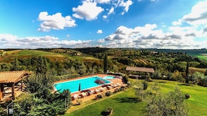 A resort with a swimming pool, lounge chairs, and a view of the surrounding countryside. - Apartment with A/C, pool, WIFI, TV, veranda, pets allowed, panoramic view, close to San Gimignano (Sughera)