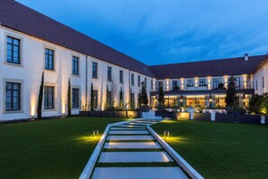 A courtyard with a central pathway, surrounded by buildings with large windows and a well-maintained lawn. - Best Western Premier Hotel & Spa Les Sept Fontaines (Tournus)