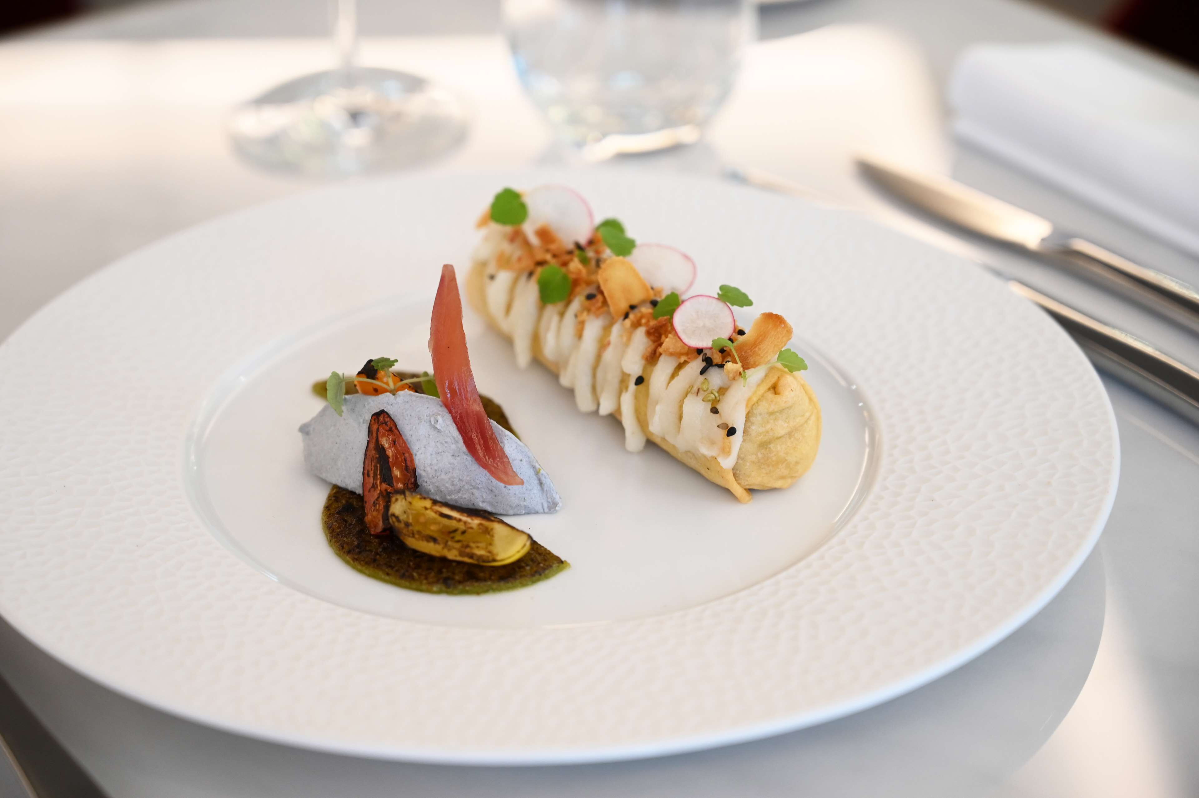 A white plate with a dessert and a small dish of sauce.