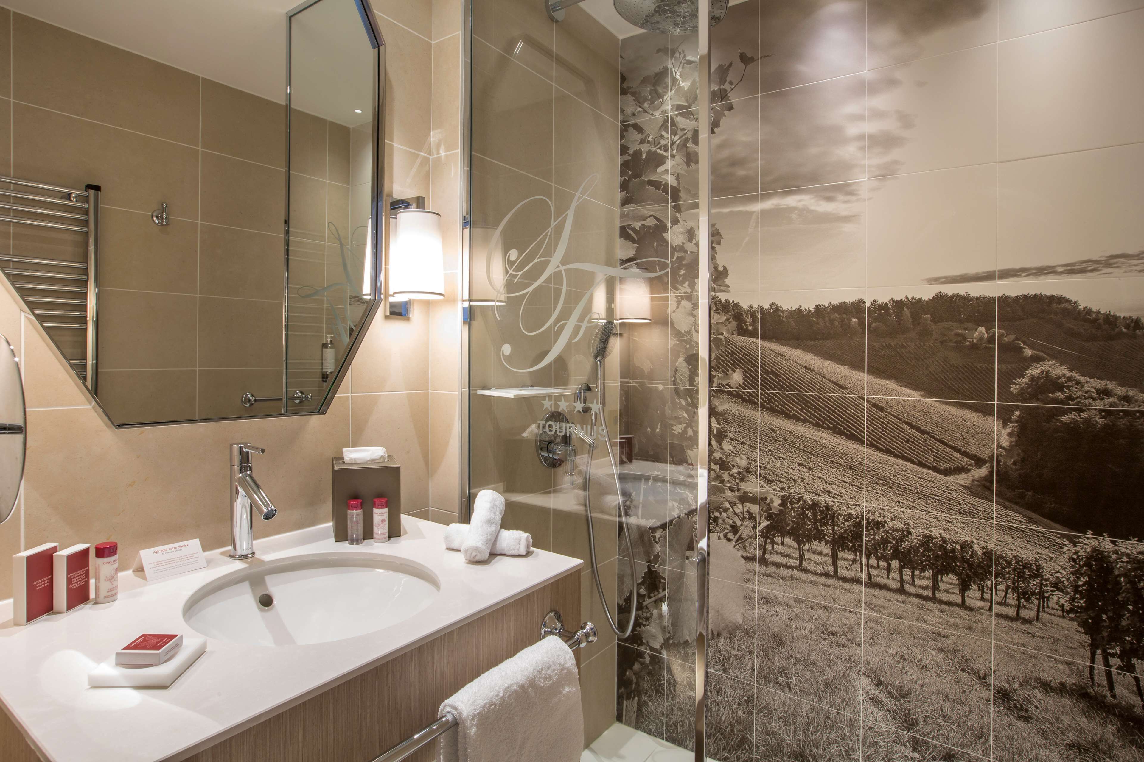 Une salle de bain moderne avec un grand miroir, un lavabo et un espace douche.