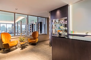 A modern hotel lobby with large windows, a reception desk, and two orange armchairs. - Best Western Premier Hotel & Spa Les Sept Fontaines (Tournus)