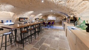 A spacious bar area with a long counter, multiple stools, and a rustic stone ceiling. - Best Western Premier Hotel & Spa Les Sept Fontaines (Tournus)